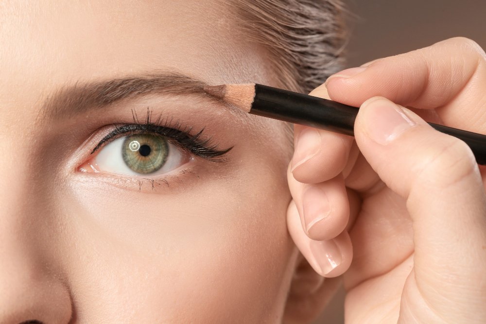 Close-up of a brow pencil being used to fill client's eyebrows