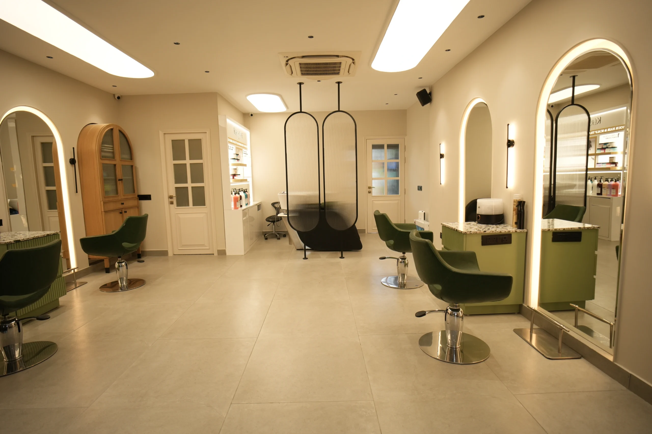 Bellance Salon spacious women's floor with green styling chairs, arched lit mirrors, wooden cabinet, and wash area beyond