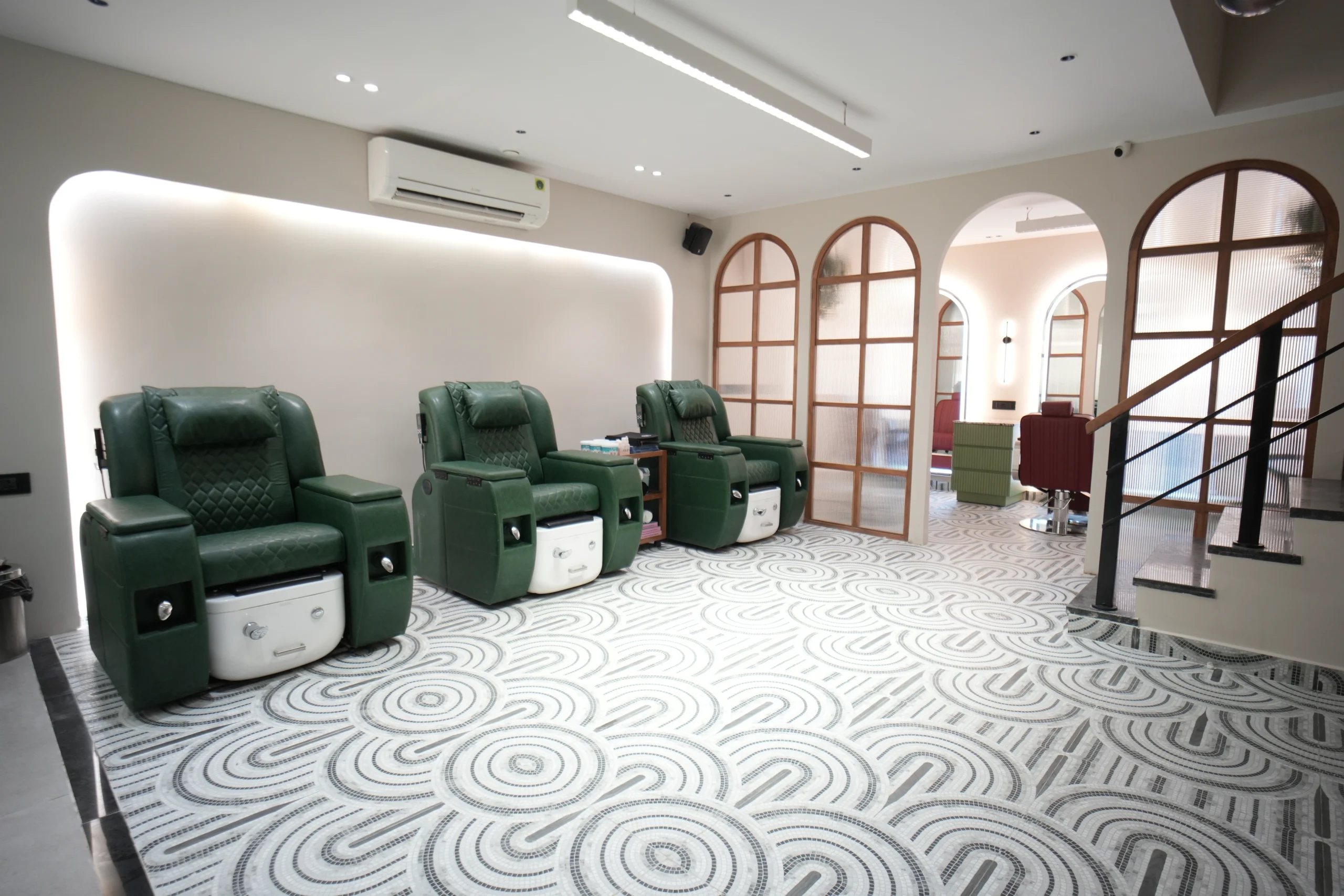Bellance Salon pedicure lounge with green recliner chairs, white foot spa units, mosaic floor, and arched wooden partitions