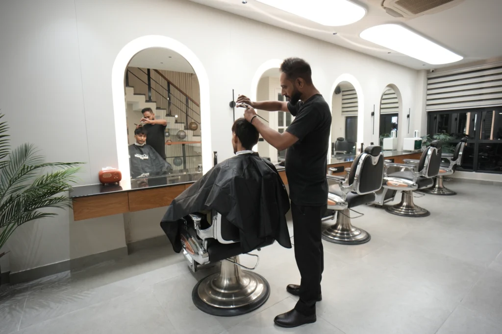 Bellance Salon barber cutting a male client's hair in chrome chair with arched mirrors in background