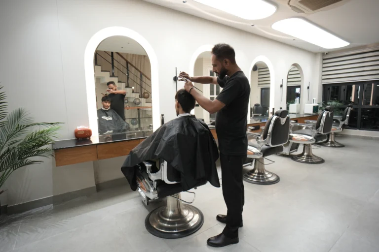 Bellance Salon barber cutting a male client's hair in chrome chair with arched mirrors in background
