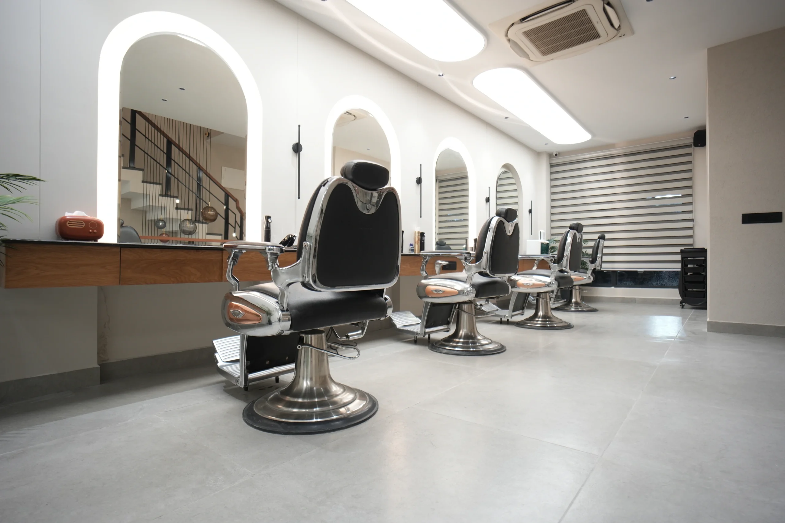 Bellance Salon barber section with black leather chrome chairs, arched mirrors, and wooden counter